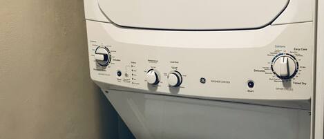 Lavadora de carga frontal con panel de control, incluyendo botones para temperatura, tamaño de la carga y programas de lavado.