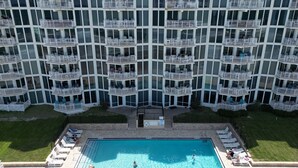 Un hotel de varios pisos con balcones, piscina y tumbonas.