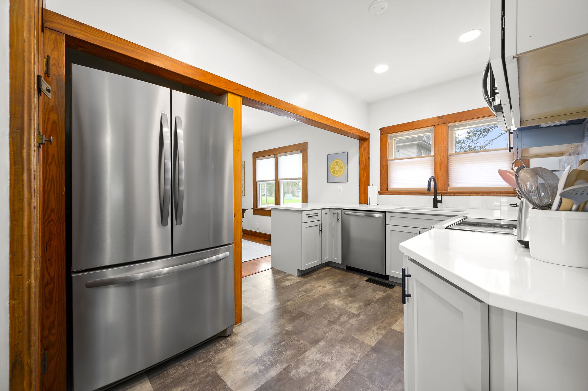 A modern kitchen with stainless steel appliances, wooden beams, and a large window providing natural light.