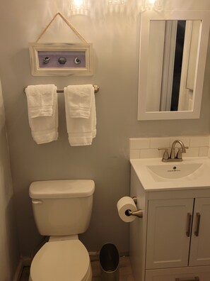A bathroom with a toilet, sink, and two towels hanging on a rack. - SEArenity and Seashells (Myrtle Beach)
