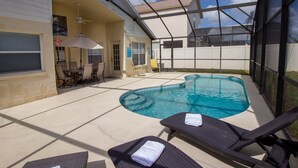 A covered outdoor swimming pool area with lounge chairs and a table. - Large 4 Bedroom Villa. 3 Miles to Disney, Private Pool, Games Room (Kissimmee)