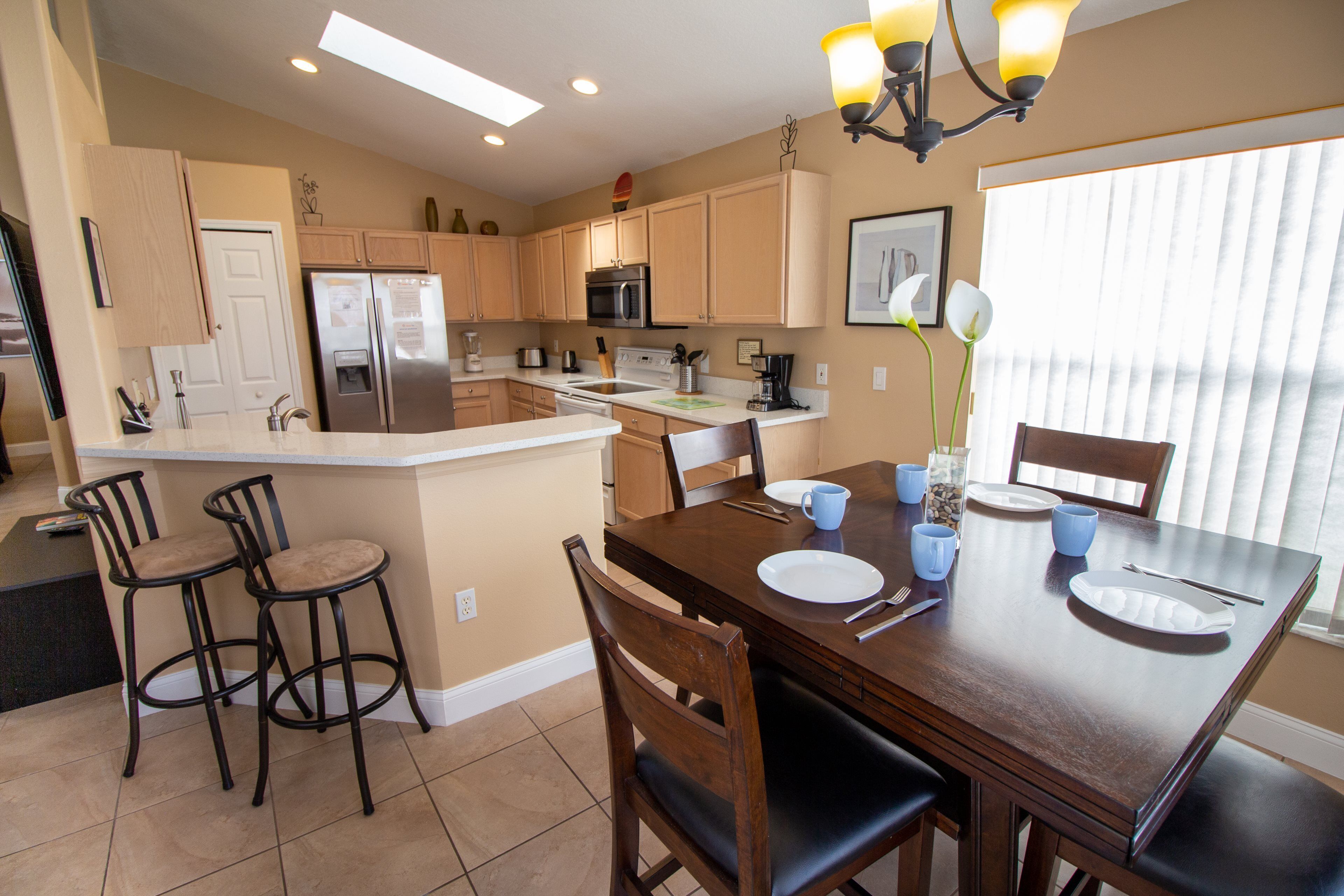 A modern kitchen with a central island, bar stools, and a dining table set for four.