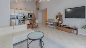 A modern living room with a sofa, a coffee table, and a TV. - Reserve Relaxing 5 Bedroom Pool Lake View (Davenport)
