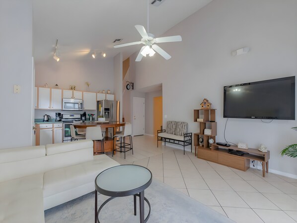 A modern living room with a sofa, a coffee table, and a TV. - Reserve Calming 5 BR Pool Home Gated Lake View (Davenport)