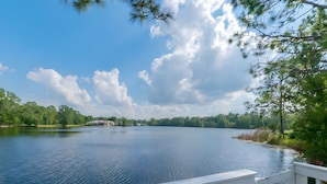 A lake with a white deck, surrounded by trees and a clear sky. - Reserve Relaxing 5 Bedroom Pool Lake View (Davenport)
