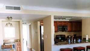 A spacious living room with hardwood floors, a dining area with wicker furniture, and a kitchen with wooden cabinets and stainless steel appliances. - Westwinds, paradise and heaven all rolled into one (Treasure Island)
