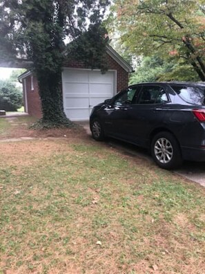 A black SUV parked in a driveway next to a brick garage.