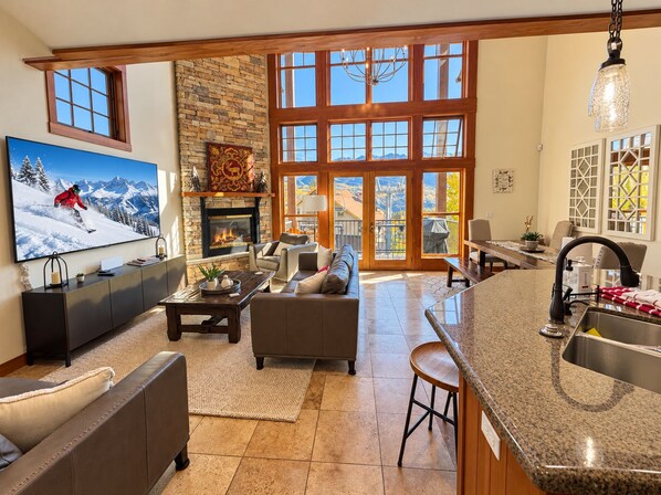 A spacious living room with a fireplace, a large TV, and a stone accent wall.