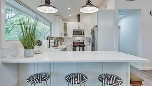 A modern kitchen with white cabinets, a central island with bar stools, and pendant lighting. - Lakefront, Private Dock, Spectacular Views, Spacious, Modern , 2 Large Decks, Firepit, Gameroom! (Bridgeport)
