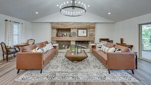 A spacious living room with a fireplace, two sofas, a coffee table, and a chandelier. - Lakefront, Private Dock, Spectacular Views, Spacious, Modern , 2 Large Decks, Firepit, Gameroom! (Bridgeport)