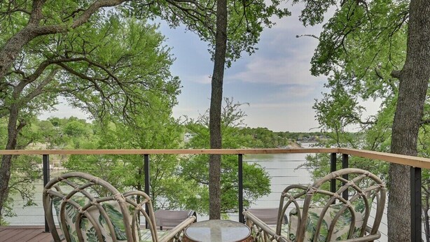 A deck with wicker chairs and a small table, overlooking a lake and trees. - Lakefront, Private Dock, Spectacular Views, Spacious, Modern , 2 Large Decks, Firepit, Gameroom! (Bridgeport)