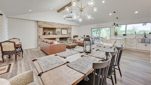 A spacious living area with a fireplace, a dining table with multiple placemats, and a kitchen in the background. - Lakefront, Private Dock, Spectacular Views, Spacious, Modern , 2 Large Decks, Firepit, Gameroom! (Bridgeport)