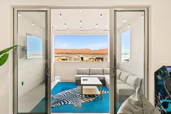 A modern living room with a glass door leading to a balcony with a desert view.