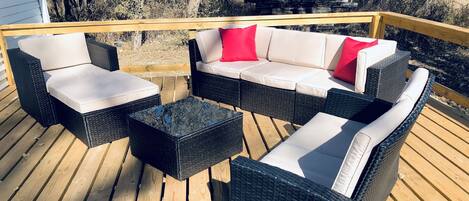 A wooden deck with wicker furniture including a sofa and chairs.