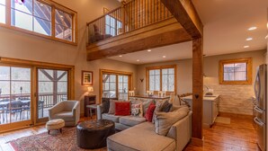 A spacious living room with a high ceiling, large windows, and a cozy seating area. - Bag End at Eagles Nest - Game room, great location in the Villages of Eagles Nest + many amenities (Banner Elk)