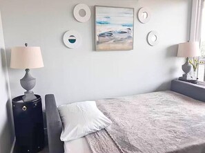 Una camera da letto con un letto, due comodini, una lampada e un quadro appeso al muro.