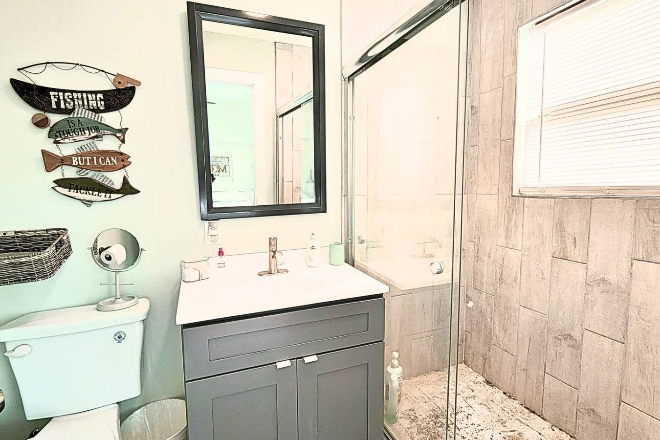 A bathroom with a toilet, sink, mirror, and shower.