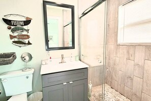 Un bagno con il water, lavandino, specchio e doccia.