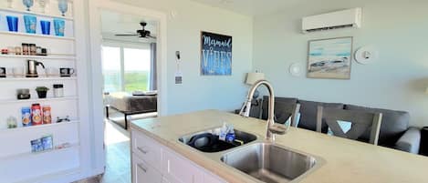 A modern kitchen with a double sink, white cabinetry, and a view of the outdoors.