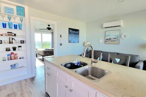 A modern kitchen with a double sink, white cabinetry, and a view of the outdoors.