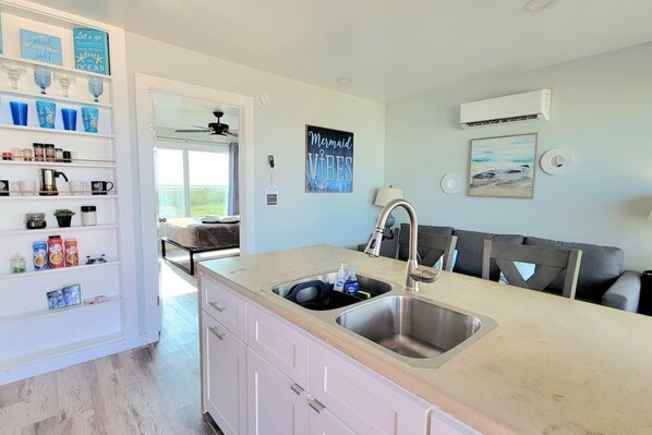Una cocina moderna con un lavamanos doble, armarios blancos y vistas al exterior.