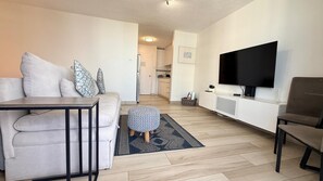 A modern living room with a sofa, ottoman, and a flat-screen TV. - CB118-St Balcony & Ocean View (Carolina)