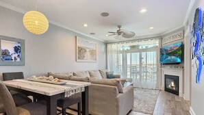 A modern living room with a fireplace, a television, and a dining area with a table and chairs.