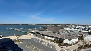 A waterfront property with a parking lot, a dock extending into the water, and a building with a sign reading 'Rusty Rudder.'