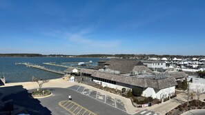 A waterfront property with a parking lot, a dock extending into the water, and a building with a sign reading 'Rusty Rudder.' - Luxurious Penthouse, King beds. Dog & ADA Friendly (Dewey Beach)