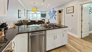 A modern kitchen with a central island, stainless steel appliances, and a dining area with a view to the living room.