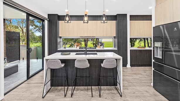 Una cocina moderna con una isla central, taburetes de bar y un refrigerador grande.