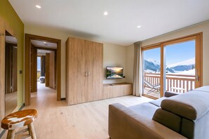 Ein Hotelzimmer mit großem Fenster, einer Couch, einem Fernseher und einem Holzschrank.