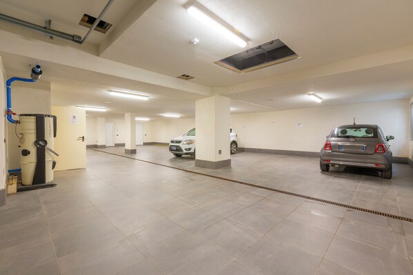 Un garaje para estacionar con varios niveles, un sistema de ventilación y algunos automóviles estacionados.