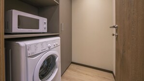 Un espace buanderie avec un lave-linge et un four à micro-ondes posé sur le dessus.