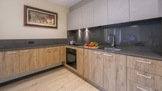 Une cuisine moderne avec des meubles en bois, un évier en acier inoxydable et un four encastré.