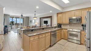 A modern kitchen with granite countertops, stainless steel appliances, and wooden cabinets. - Azure 110 walkout closest unit to beach access, no Elevator Rides! Beach Service (Fort Walton Beach)