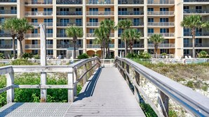 A multi-story hotel with balconies, a pool area, and a wooden boardwalk leading to the entrance. - Azure 110 walkout closest unit to beach access, no Elevator Rides! Beach Service (Fort Walton Beach)