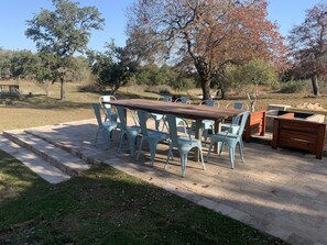 Un patio al aire libre con mesa y sillas de madera, una parrilla y una chimenea de piedra.