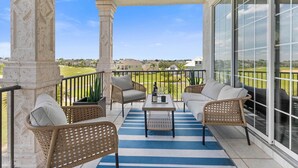 A balcony with wicker furniture, a table, and a view of a golf course. - 5 Bedroom Resort Villa w/Private Pool + Hot Tub | 1 Exit from Disney (Kissimmee)