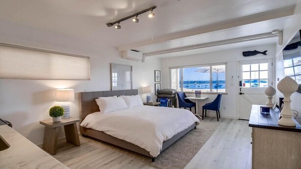 Ein modernes Hotelzimmer mit einem großen Bett, einem Schreibtisch und Blick auf das Meer.