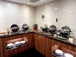A buffet setup with multiple food stations, a wooden counter, and a sign indicating the location.