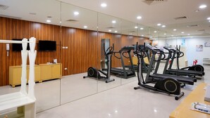 Un gimnasio con equipo de ejercicio, una pared de madera, un televisor y un espejo.
