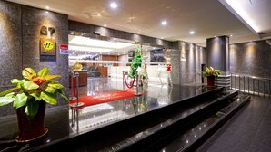 Un moderno vestíbulo de hotel con mostrador de recepción, alfombra roja y decoración navideña.