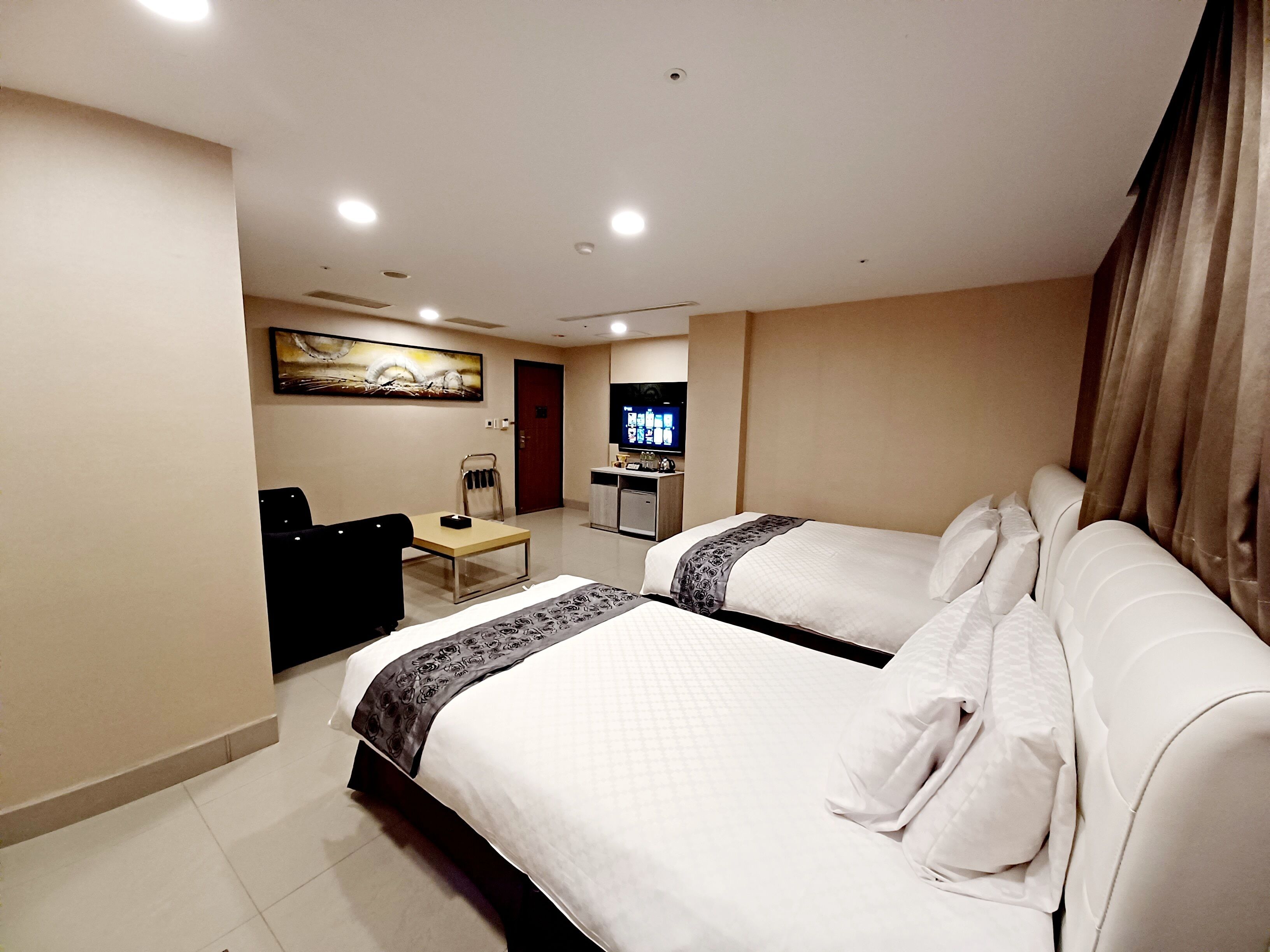 Een hotelkamer met twee bedden, een bureau, een televisie en een schilderij aan de muur.