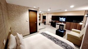 Una habitación de hotel moderna con una cama grande, un escritorio, un televisor y una zona de estar.