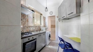 A compact kitchen with a gas stove, microwave, and washing machine.