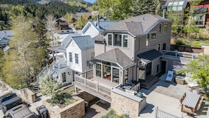 A two-story house with a balcony, a covered patio, and a stone retaining wall.