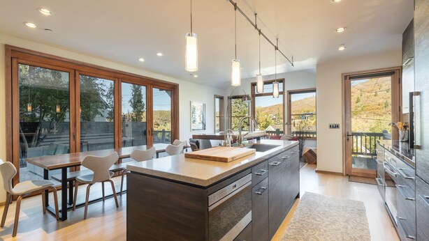 A modern kitchen with a large island, wooden cabinetry, and pendant lighting.