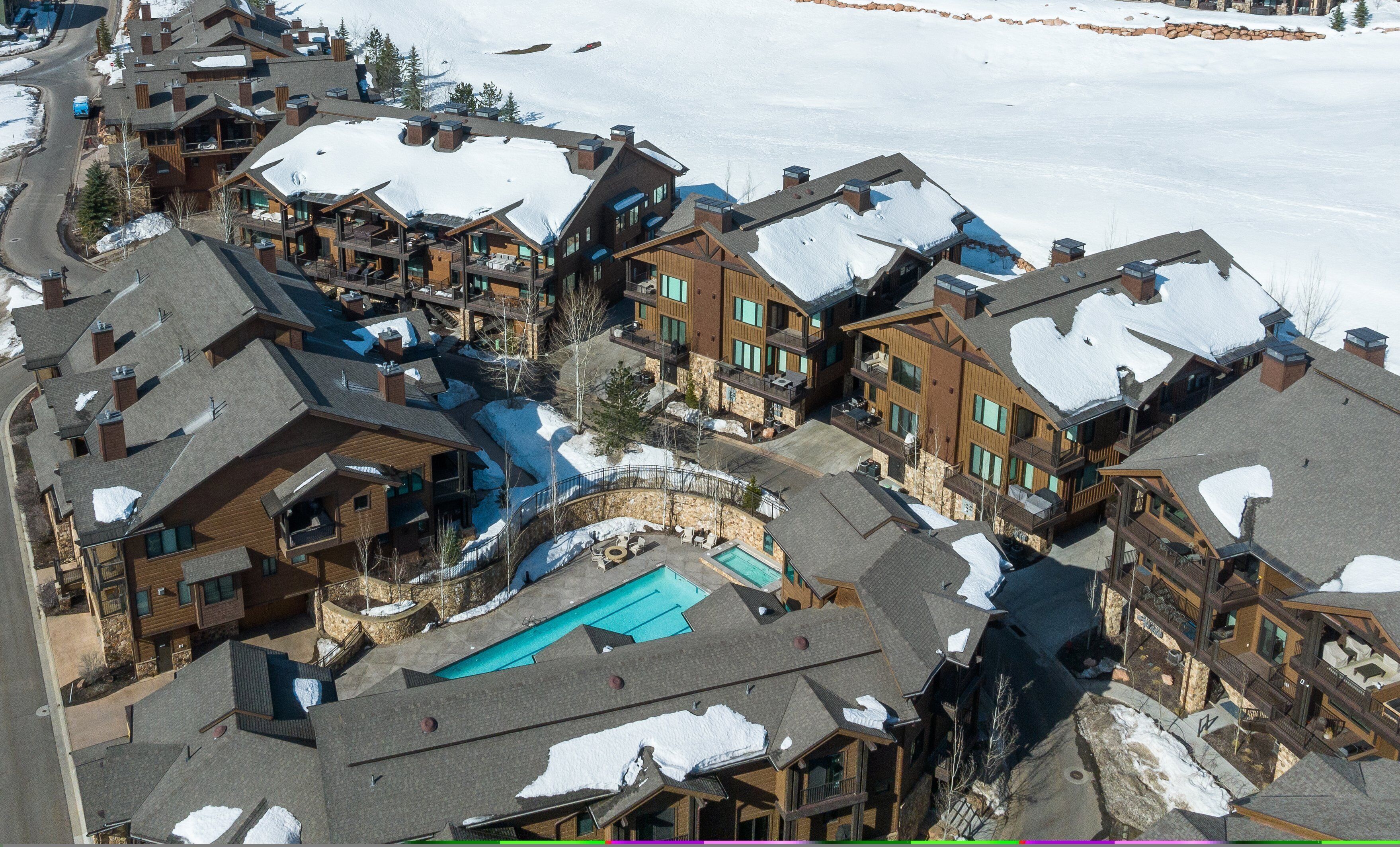 Un complejo turístico nevado con varias construcciones, piscina y telesilla.