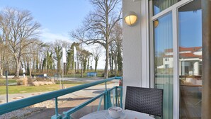 Een balkon met een tafel, een stoel en een kop koffie.